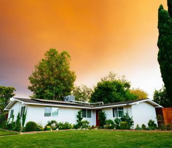 a photo of a white, one-story home with a colorful sky behind it