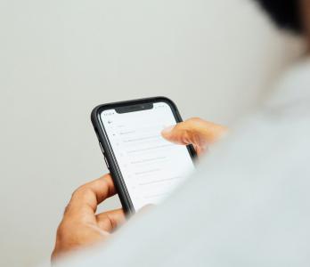 photo of the back of a man looking at the screen of an iPhone. The screen is not legible.