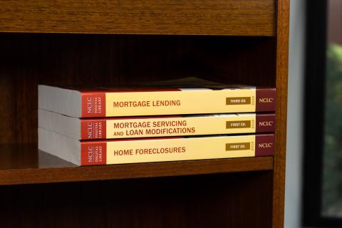 stack of books in the NCLC Consumer Law Practice Series that pertain to housing: Home Foreclosures, Mortgage Servicing and Loan Modifications, and Mortgage Lending