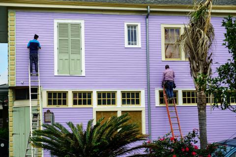 photo of people on a ladder painting a house purple