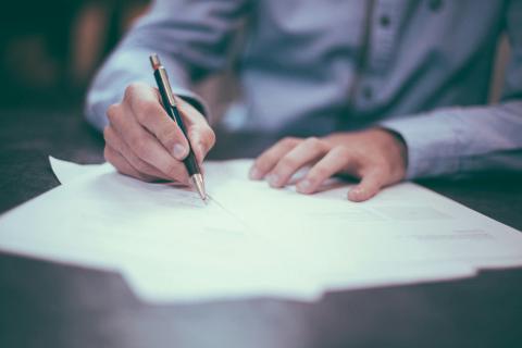 photograph of a white person's hands annotating a document with a pen